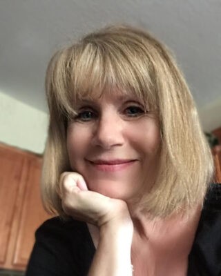 A woman with blonde hair and bangs posing for the camera.